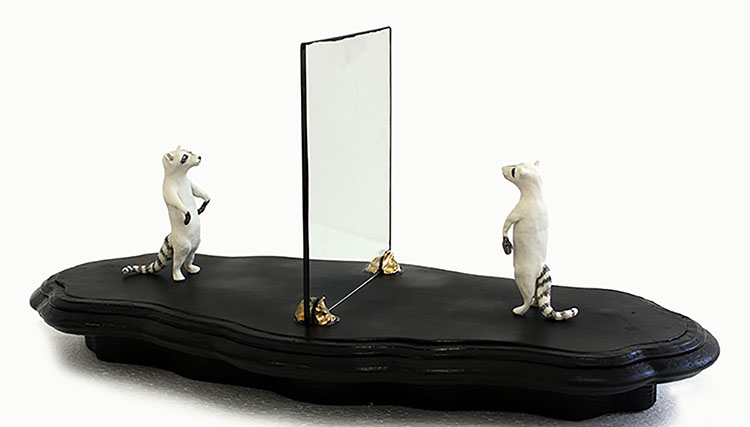 Foto av konstverk föreställande tvättbjörnar i lera som tittar på varandra genom en spegel