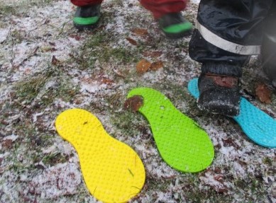 En gul, grön och blå fot i plast som ligger på marken.